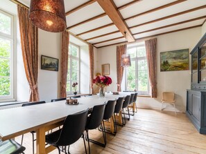 A dining area with a long table, black chairs, and a wooden floor. - Limburg Mansion with Spa near Forest (Swolgen)