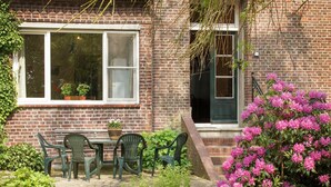 A brick house with a garden patio, a table with chairs, and a door.