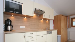 A modern kitchen with white cabinetry, a built-in microwave, and a coffee maker on the counter. - Stylish Flats in Uderns near Ski Lift (Uderns)