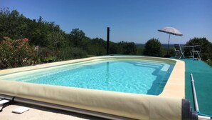 Una piscina rectangular amb aigua cristal·lina blava, envoltada per una terrassa color beix.