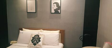 Una habitación de hotel con cama, mesita de noche y hervidor de agua instalado en la pared.