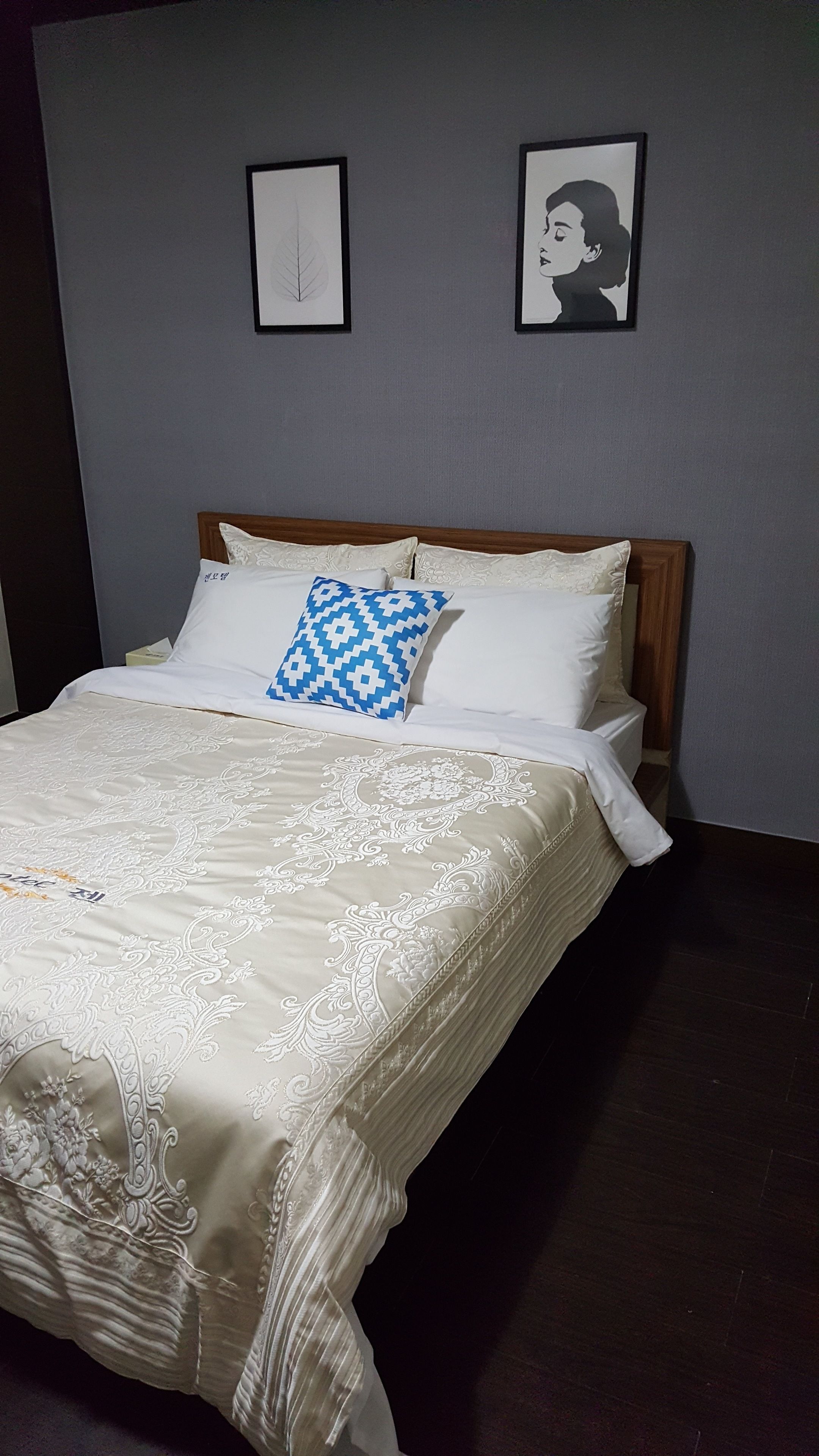 Un lit bien fait, avec une couvre-lit à motifs, deux oreillers et une tête de lit en bois.