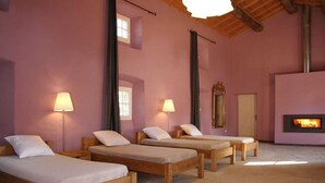 Ein Zimmer mit vier Holzbetten, einem Kamin und zwei Stehlampen.