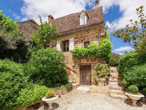 Ein Haus aus Stein mit einem Ziegeldach, einer Holztür und einer kleinen Treppe, die zum Eingang führt.