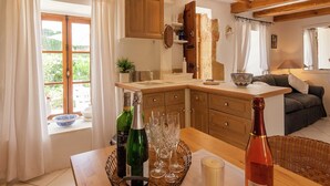 A cozy kitchen with wooden cabinets, a dining table with wine bottles and glasses, and a view of the outdoors.