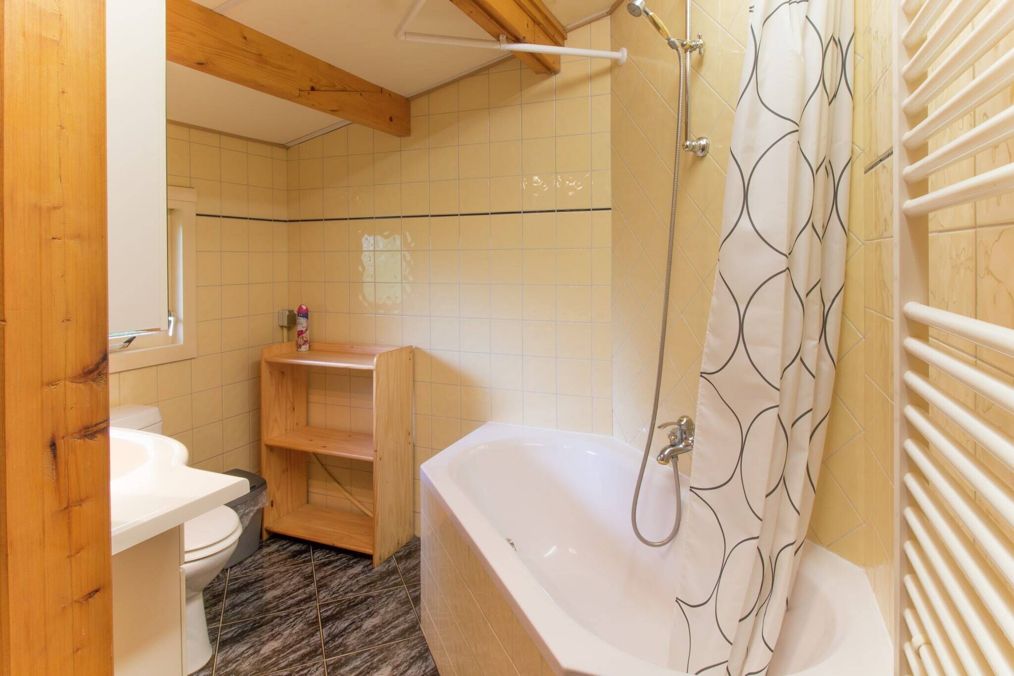 Un baño con bañera, inodoro y estante de madera.