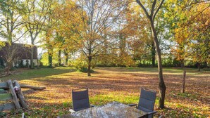 An outdoor seating area with a table and chairs, surrounded by trees with autumn leaves. - Bauernhaus nahe Langlingen Badesee (Langlingen-Hohnebostel)