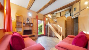 A cozy living room with a fireplace, wooden furniture, and a staircase leading to an upper level. - Bauernhaus nahe Langlingen Badesee (Langlingen-Hohnebostel)