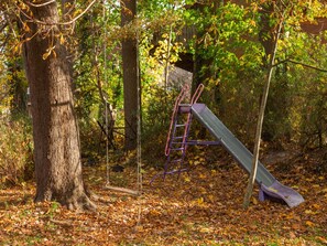 A playground with a slide and a swing set in a wooded area. - Bauernhaus nahe Langlingen Badesee (Langlingen-Hohnebostel)