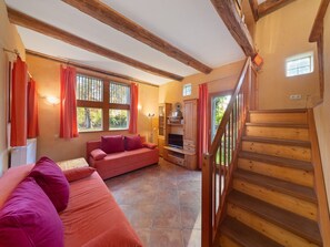 A cozy living room with a wooden staircase, a sofa, and a television.