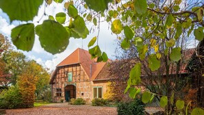 A traditional half-timbered house with a brick facade, a green door, and a gravel driveway. - Bauernhaus nahe Langlingen Badesee (Langlingen-Hohnebostel)