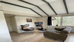 Ein modernes Wohnzimmer mit einer Couch, einem Sessel, einem Fernseher und einem Kamin.