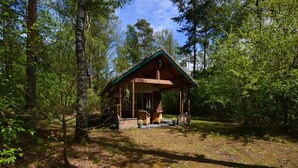 Eine rustikale Holzhütte mit Veranda, umgeben von dichtem Wald.