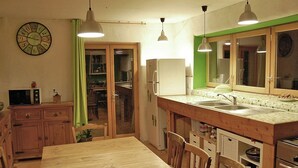 A compact kitchen with a wooden table, chairs, a refrigerator, a microwave, and a sink. - Pretty Villa With Private Pool in Montadet France (Montadet)