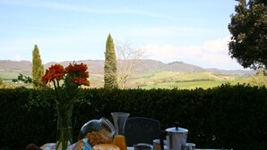 A table set outdoors with breakfast items, a cake, and a view of rolling hills. - Spacious house in Pienza (Pienza)