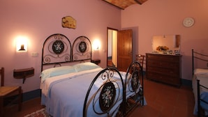 A bedroom with a bed, a dresser, a chair, a wooden door, and a wall clock. - Spacious house in Pienza (Pienza)