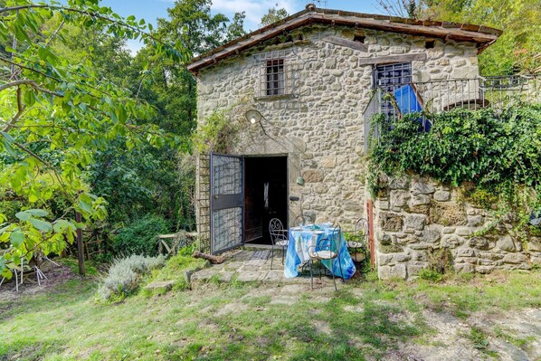 A stone building with a rustic exterior, a door, and a table with a tablecloth.