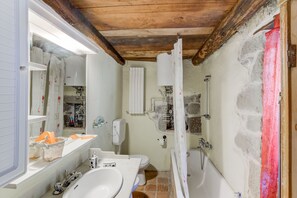 A bathroom with a wooden ceiling, a bathtub, a shower, a toilet, and a sink.