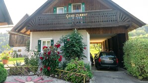 Ein traditionelles Chalet mit Holzfassade, einem Balkon mit grünen Fensterläden und einem Auto auf der Einfahrt.
