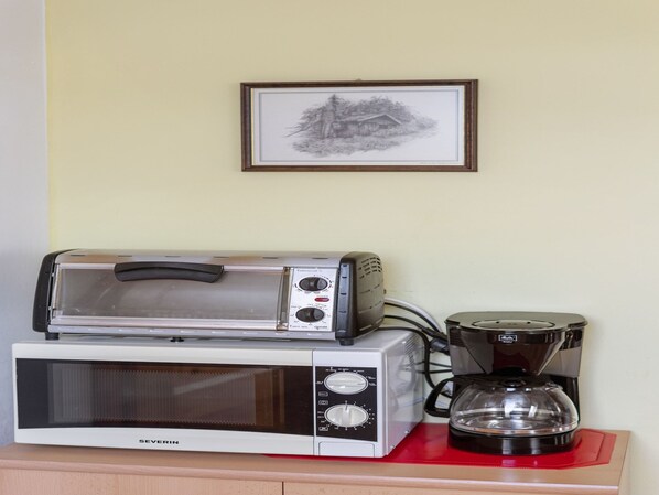 Una cucina con forno a microonde, tostapane e macchina da caffè su un piano di lavoro.