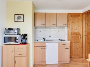 Une cuisine de taille réduite, dotée de meubles en bois, d’un four à micro-ondes, d’un grille-pain et d’un lave-vaisselle.