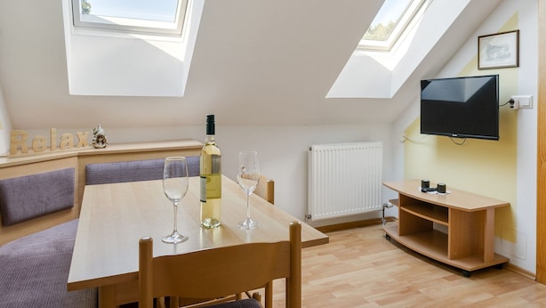 Ein modernes Schlafzimmer im Loft-Stil mit Dachfenstern, einem Bett, einem Fernseher und einem Essbereich mit Tisch und Stühlen.