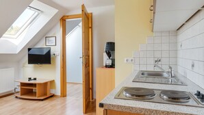 Eine moderne Küche mit Einbauherd, Spüle und Kaffeemaschine. Es gibt einen Holzkasten und ein an der Wand befestigtes Fernsehgerät.