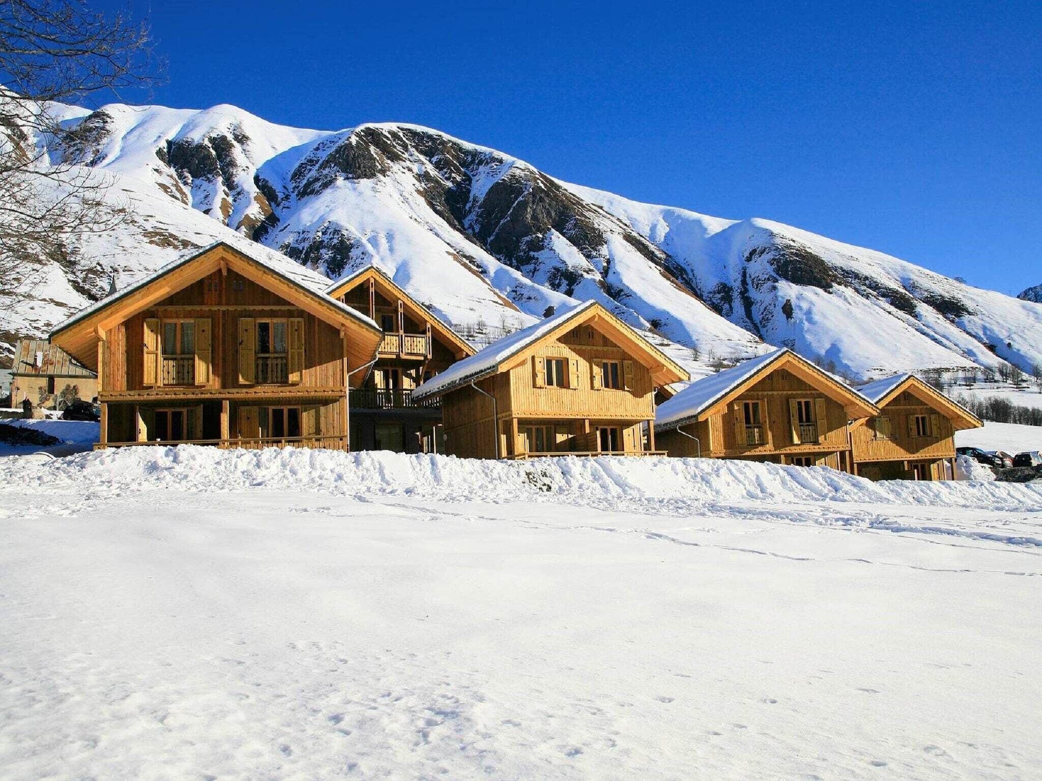 Une rangée de cabanes en bois, avec une montagne enneigée en toile de fond.