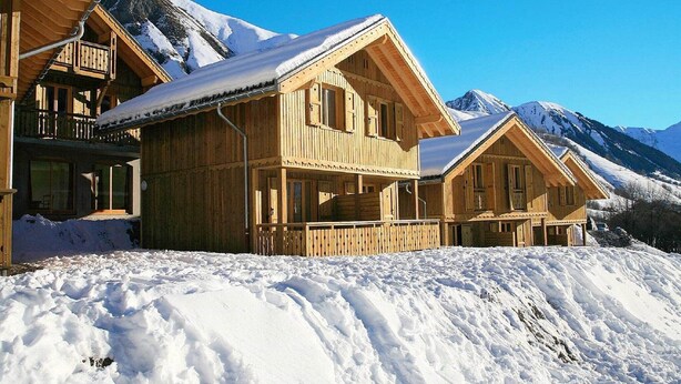A wooden chalet with a balcony and a snow-covered mountain backdrop. - Scenic Chalet Apartment for Groups (St. Sorlin D'arves)