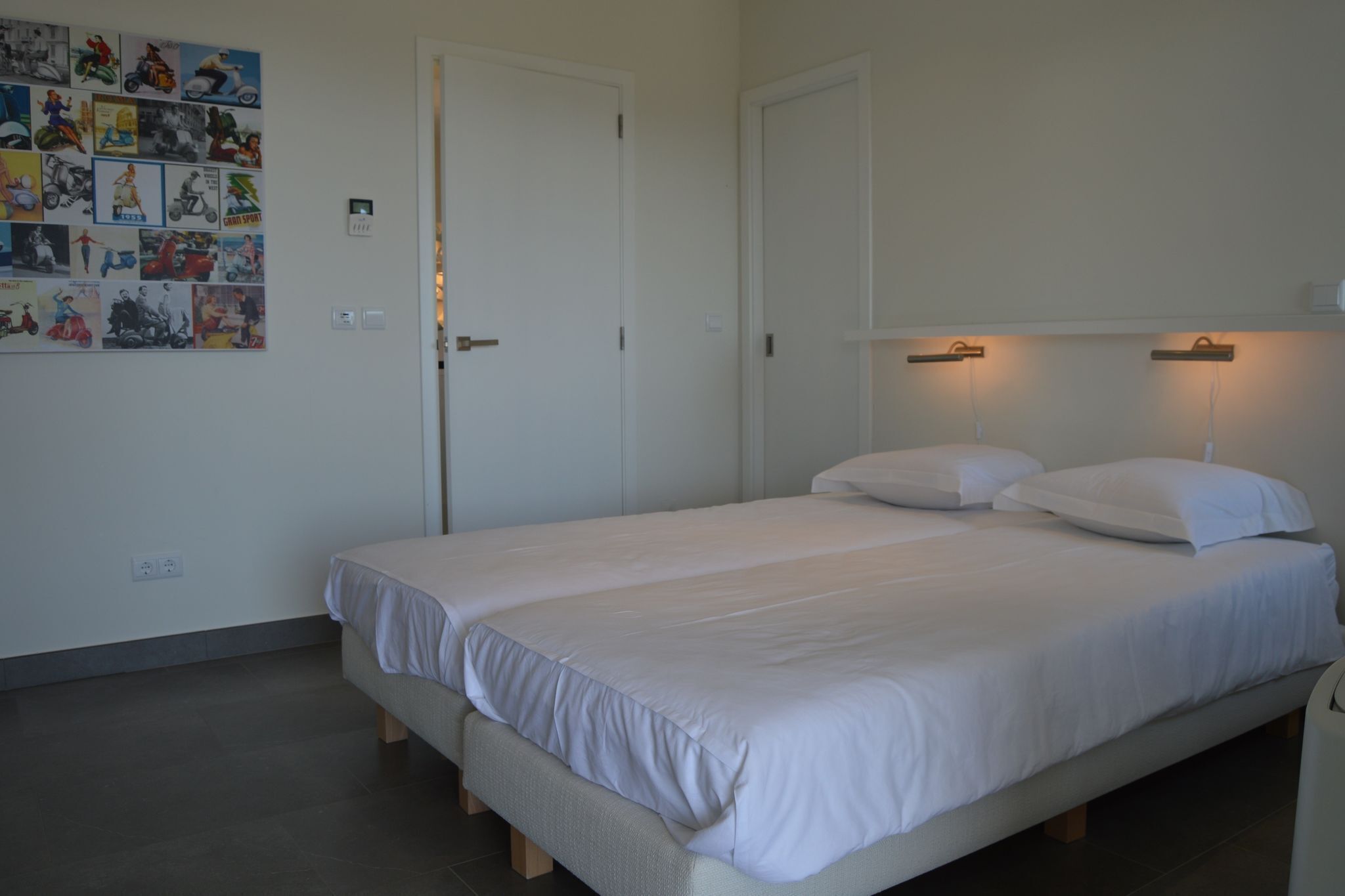 A bedroom with a single bed, a wall-mounted light, and a door.