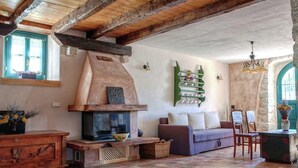 A rustic living room with exposed wooden beams, a fireplace, a sofa, and a dining area. - Villa on Krk with Pool and Outdoor Kitchen (Krk - Malinska)
