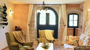 A cozy living room with a stone fireplace, a green armchair, a floral sofa, and a small table with decorative items. - Villa on Krk with Pool and Outdoor Kitchen (Krk - Malinska)