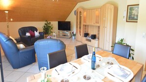 Una sala de estar moderna con comedor, techo de madera y armarios empotrados de madera.