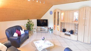 Una sala de estar acogedora con techo de madera, sofá de cuero, televisor y armarios empotrados de madera.