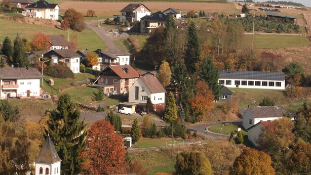 Un pueblo rural con casas, una iglesia y un edificio con paneles solares.