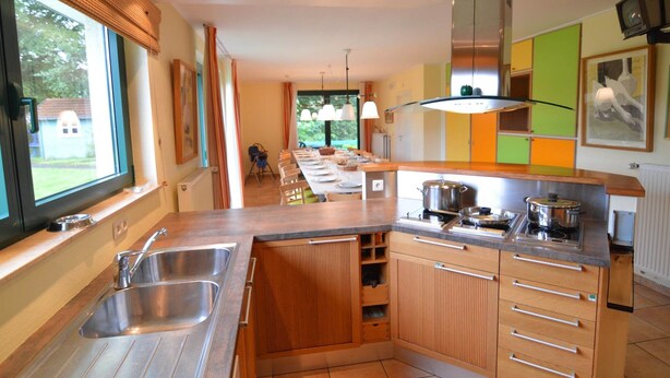 A modern kitchen with a large island, stainless steel appliances, and a view to the dining area.