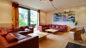 A modern living room with leather sofas, wooden flooring, and a large window.