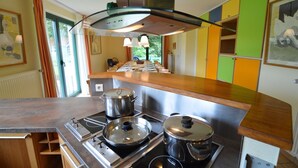 A modern kitchen with stainless steel appliances, a wooden countertop, and a view of the dining area.