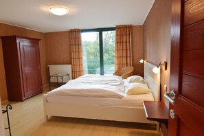 Une chambre à coucher avec un lit, une armoire en bois, un radiateur et une fenêtre avec des rideaux.