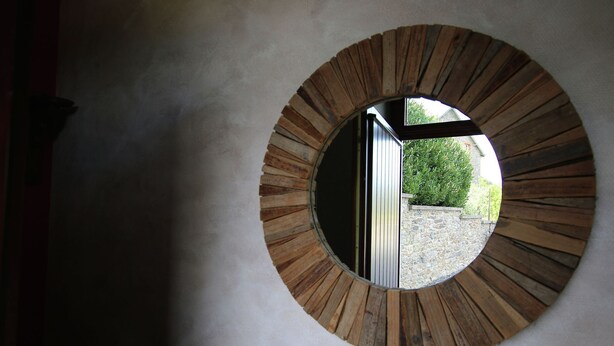 Un miroir rond, avec un cadre en bois, accroché au mur.