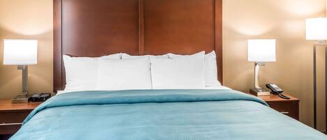 A hotel room with a large bed, two bedside tables, and two lamps.