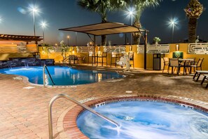 Un área de piscina con dos jacuzzis, una zona de estar cubierta y mobiliario exterior.