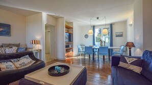 A modern living room with a sofa, coffee table, and dining area with chairs and a table. - Pavilion Stay in Dordogne (St. Medard D'excideuil)