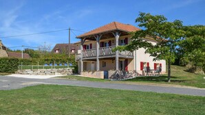 A two-story building with a balcony, a stone wall, and a grassy area in front. - Pavilion Stay in Dordogne (St. Medard D'excideuil)