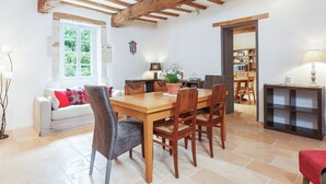 A dining area with a wooden table and chairs, a sofa, and a bookshelf.