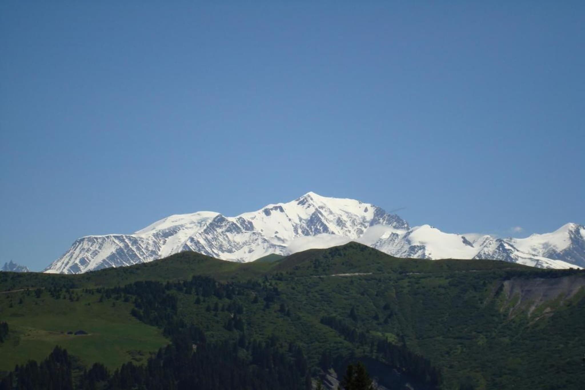 A mountain range with snow-capped peaks and a forested valley.