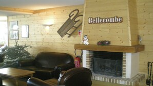 Ein gemütliches Zimmer mit Kamin, Holzwand, einer Couch und einem Tisch.