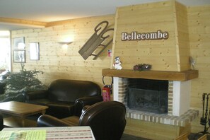 Ein gemütliches Zimmer mit Kamin, Holzwand, einer Couch und einem Tisch.