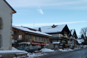 A snow-covered street with buildings, including a café and a sports shop.
