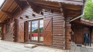 A wooden cabin with a large sliding door, stone steps, and a view of the mountains. - Chalet in La Bresse near Forest & Lake (La Bresse)